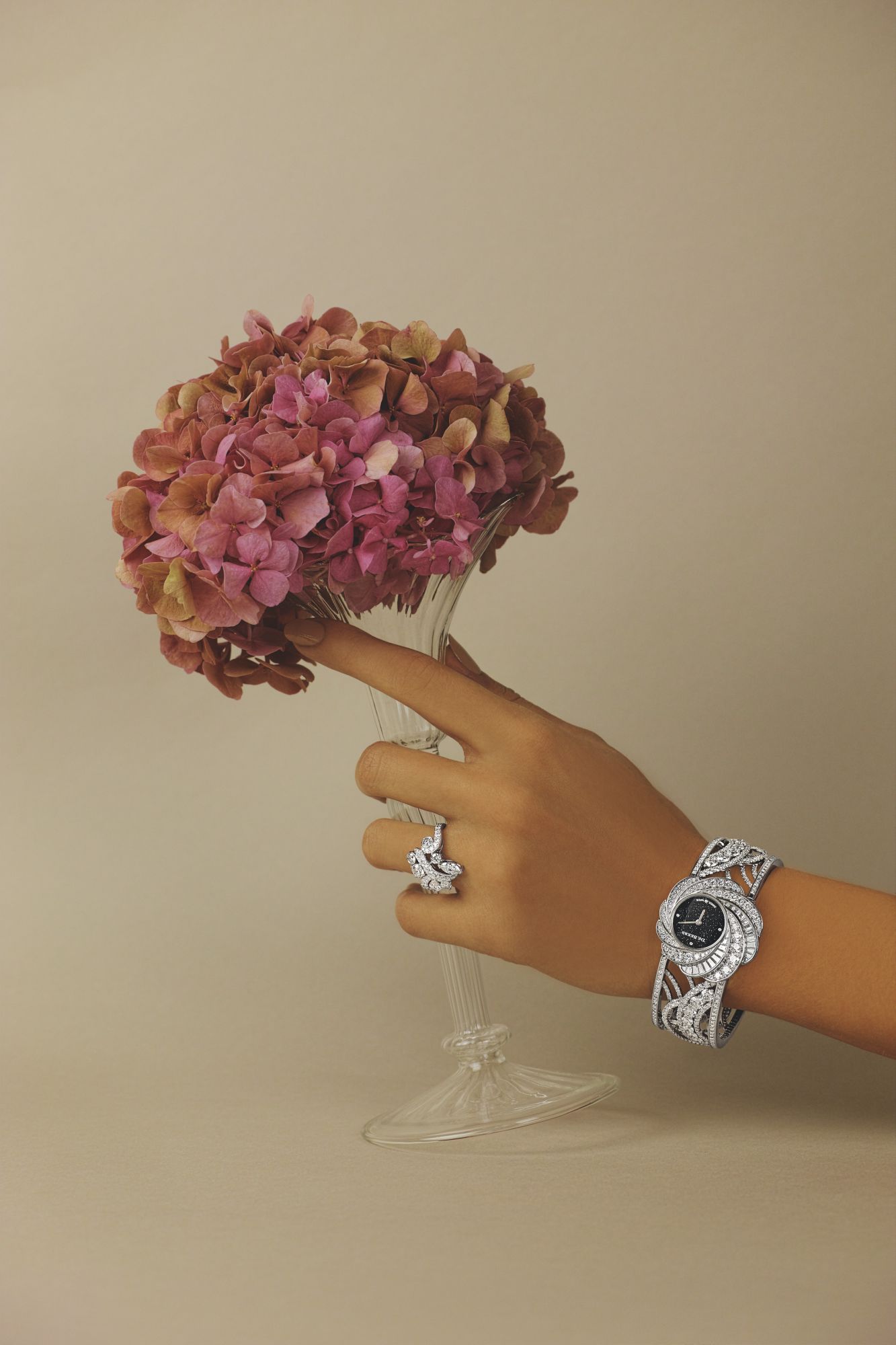 Adonis Rose Cluster ring in white gold set with white diamonds; Aria High Jewellery Unique Cuff Watch with aventurine dial surrounded by white diamonds, both by De Beers