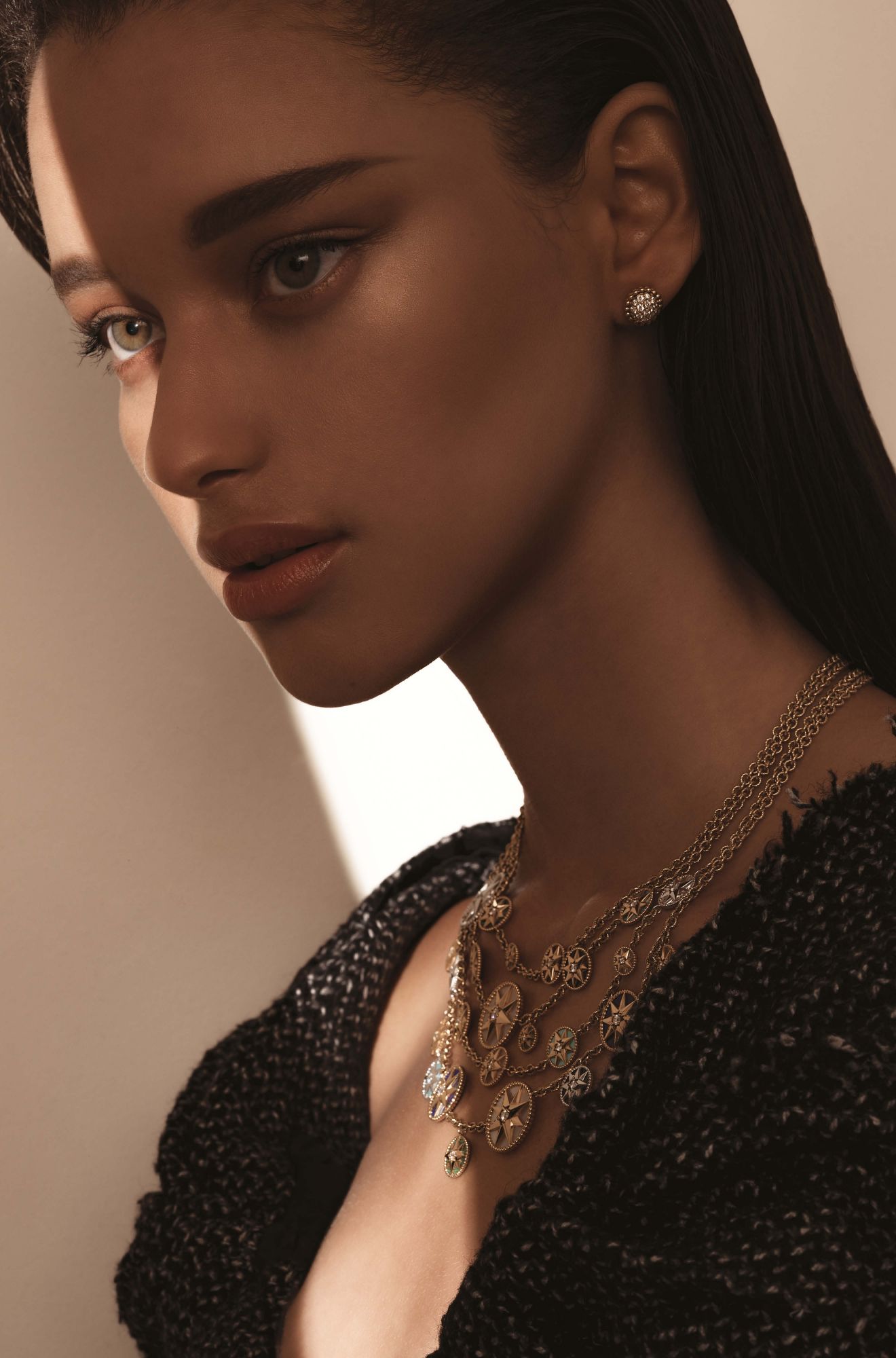 Perlée earring in yellow gold set with diamonds, by Van Cleef & Arpels; Rose des Vents necklace in yellow and white gold set with diamonds, mother-of-pearl, lapis lazuli, malachite, turquoise, onyx, tiger eye, cornelian and pink opals, by Dior; dress by Prada