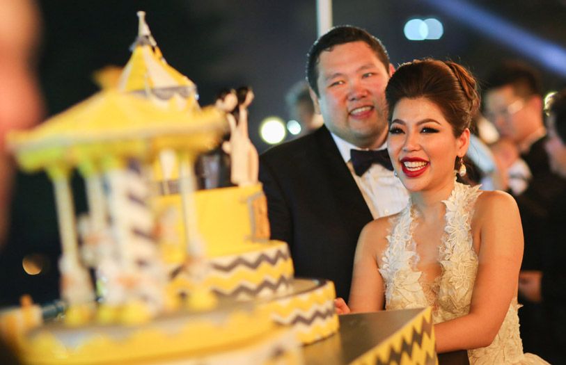 Benjamin Yong and Elizabeth Lee cutting their carnival-themed wedding cake.