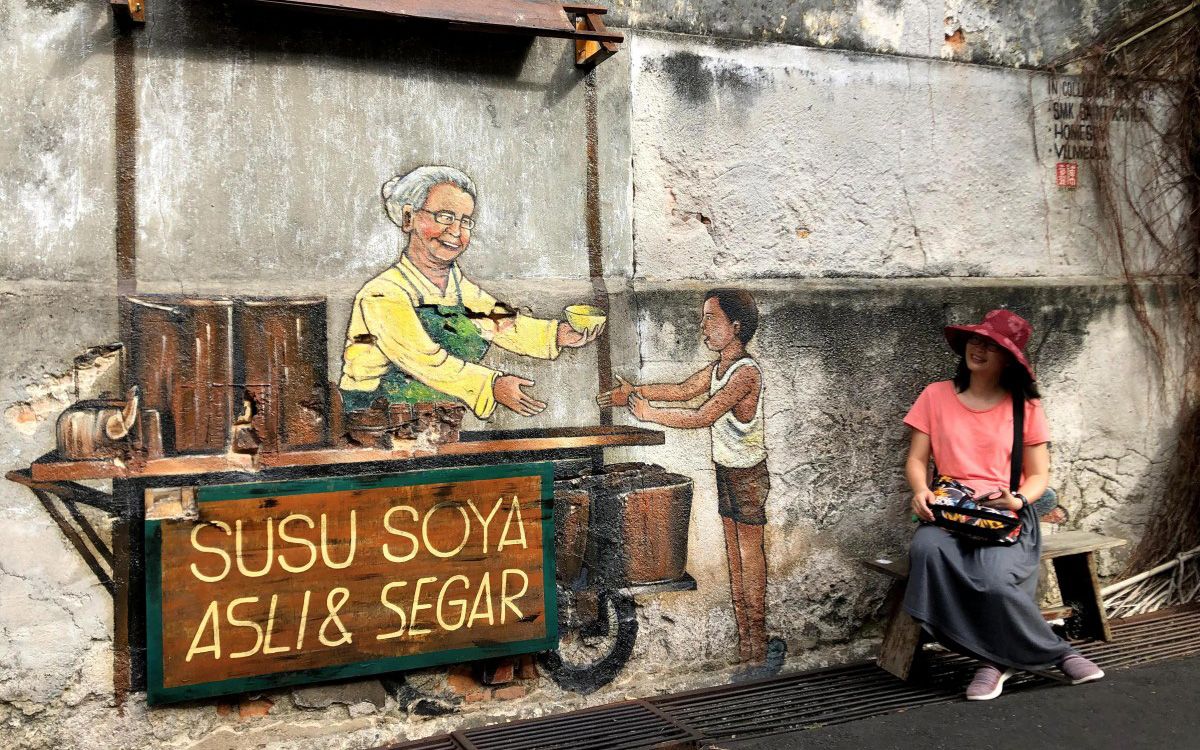 A tourist posing with a mural in Georgetown, Penang. Photo: Chung Kevin