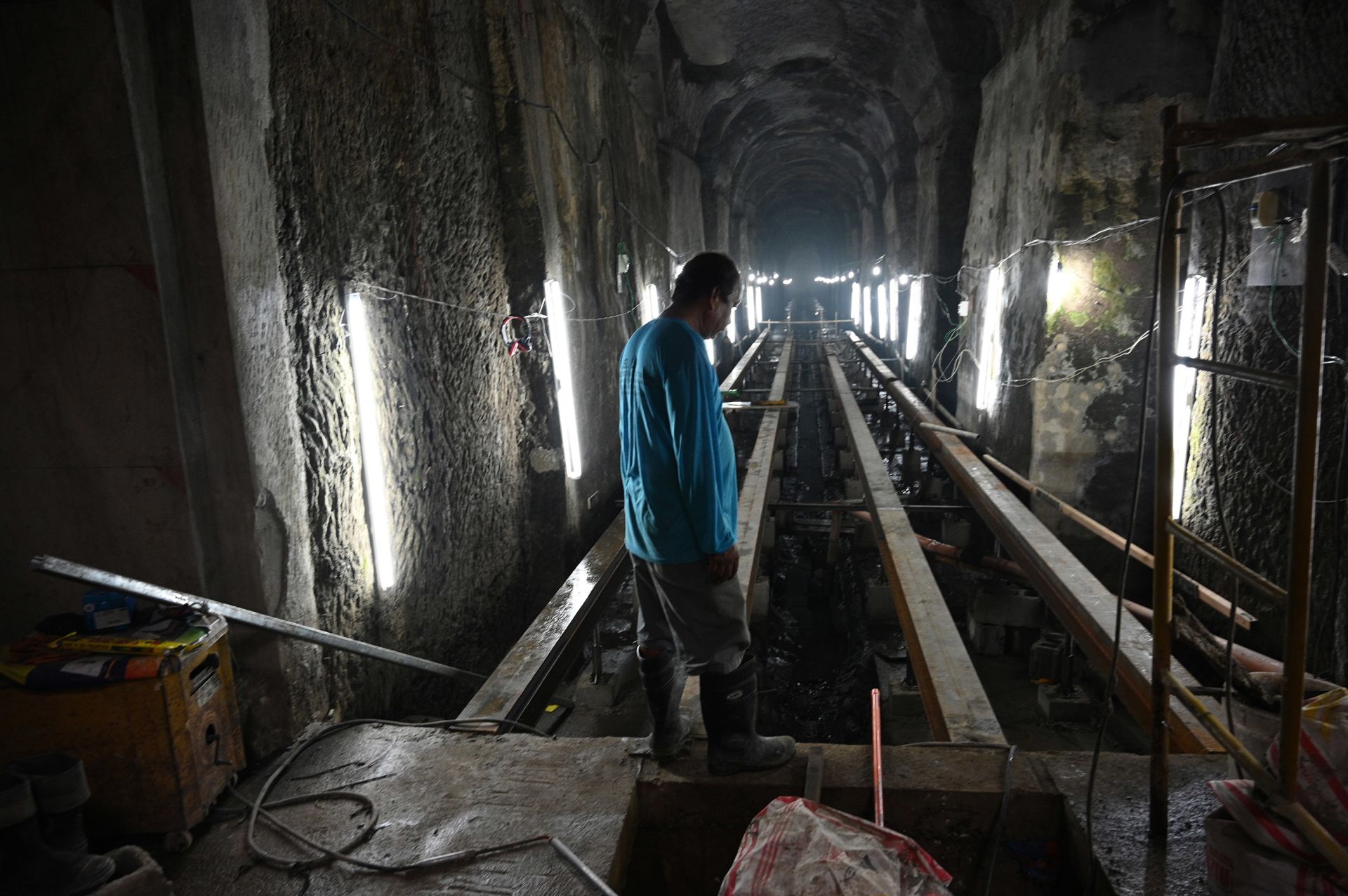 In this photo taken on November 6, 2019, a worker stands near the entrance of the El Deposito, a Spanish-era water reservoir being rehabilitated for tourism, in San Juan town, suburban Manila. - Vaulted ceilings and rows of stone columns stretch into the humid darkness deep below the Philippine capital, where workers are transforming an over century-old underground reservoir into a draw for tourists. (Photo by Ted ALJIBE / AFP) / TO GO WITH AFP STORY: Philippines history architecture