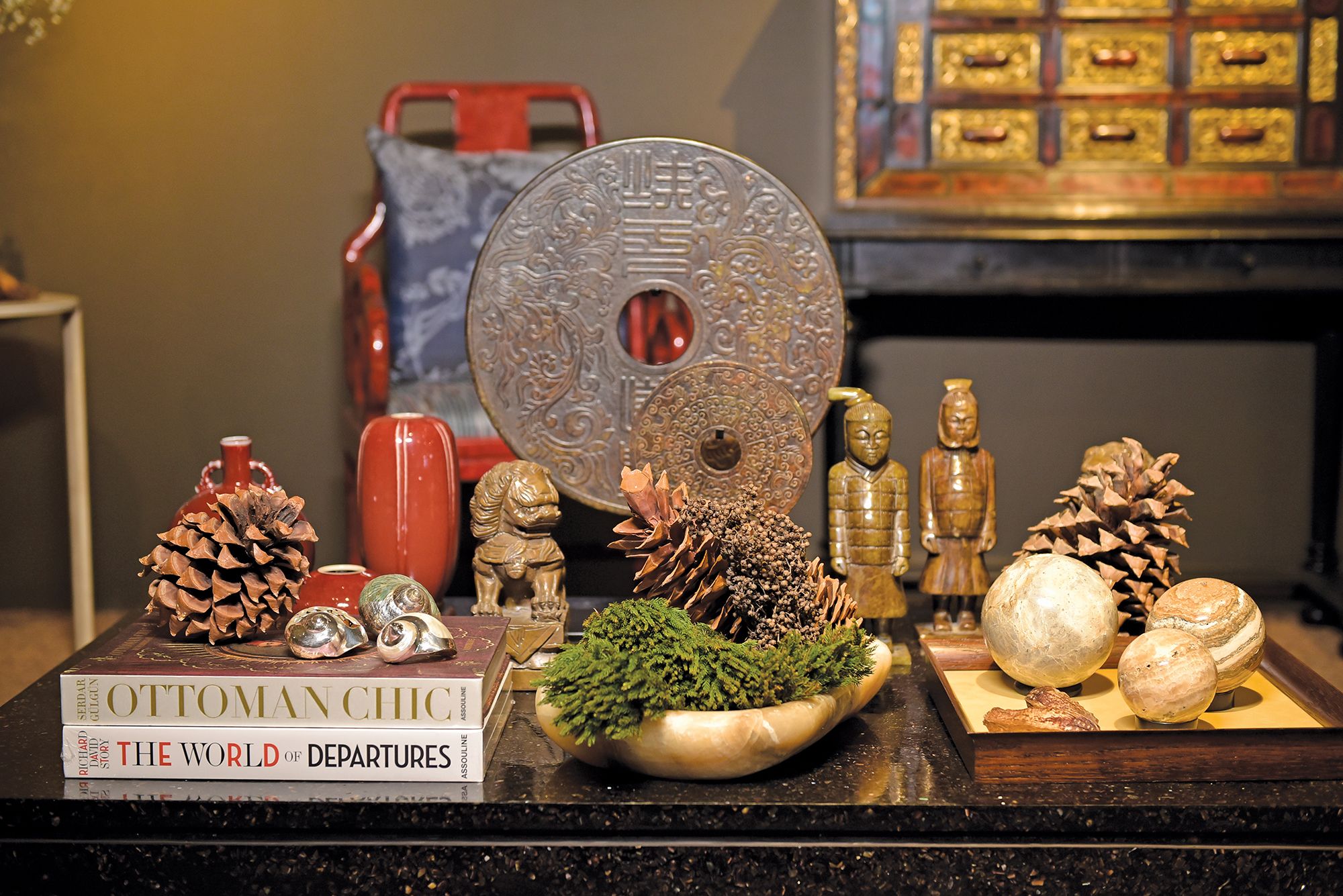 Carved from antique jade, Chinese warrior figurines and discs in shades of deep, crocodile green are chic additions to any table setting, balanced off with lighter stone. The Evergreens and pinecones blend seamlessly into the setting, for a delicate holiday touch