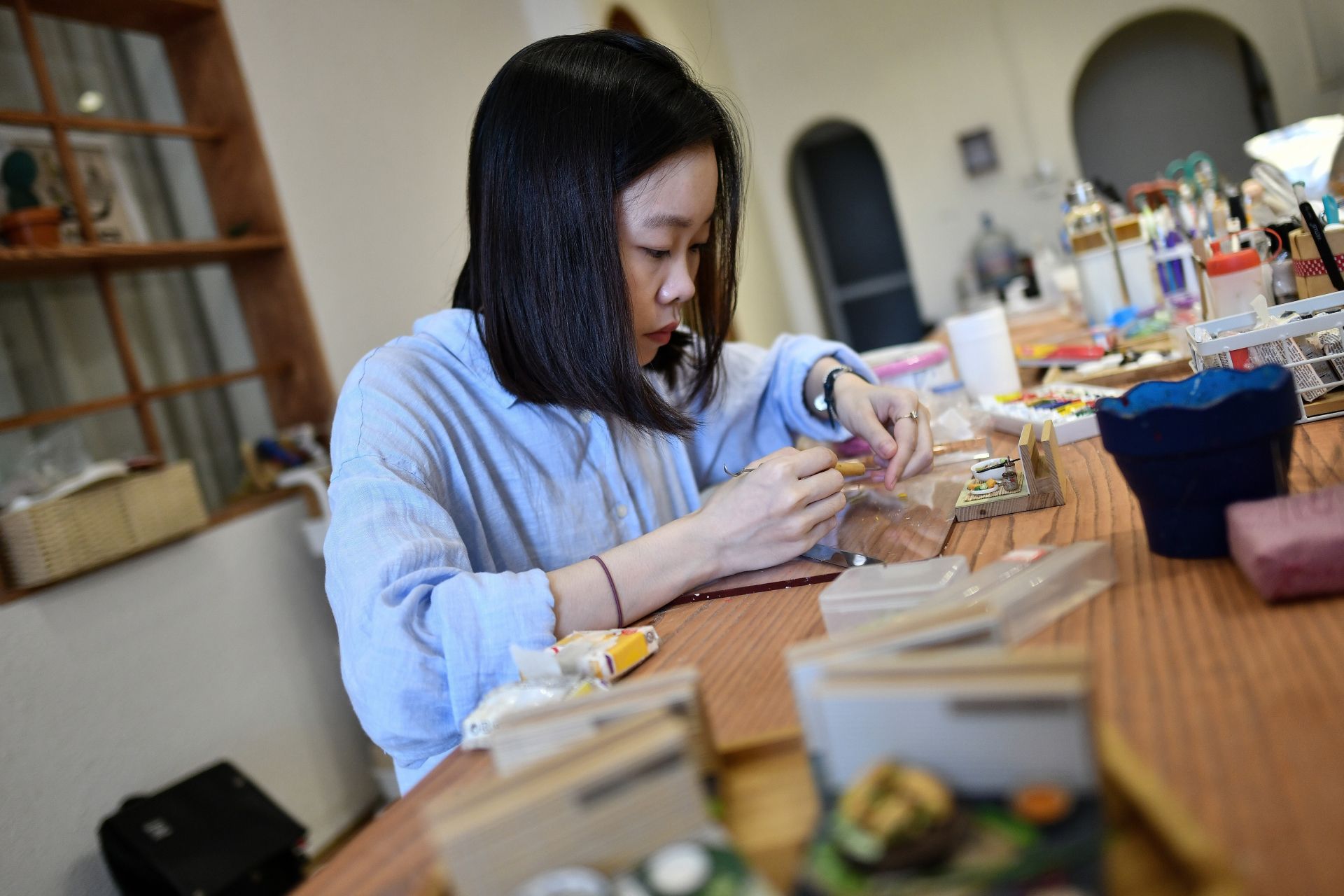 This photograph taken on August 18, 2020 shows miniature artist Nguyen Thi Ha An working at her studio in Hanoi. - An -- a 28-year-old architecture graduate -- began crafting food miniatures made from clay a year ago, spotting a chance to capitalise on the world's growing love for Vietnamese cuisine. (Photo by Manan VATSYAYANA / AFP)