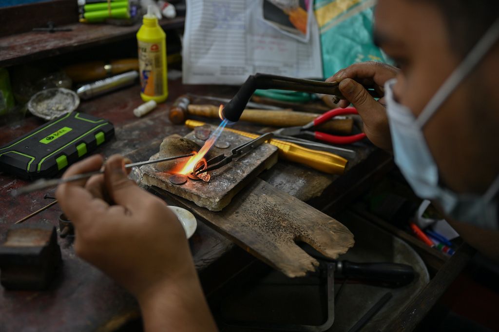 This picture taken on November 8, 2020 shows a jewellery craftsman heating a ring with a torch at the Makmur Gold workshop in Kota Bharu in Malaysia's Kelantan state. - Demand for the safe-haven commodity has soared in Malaysia during the coronavirus pandemic and it is not only professional investors who are cashing in, but small businesses too. (Photo by Mohd RASFAN / AFP) / TO GO WITH Health-virus-Malaysia-economy-gold, FOCUS by Patrick Lee