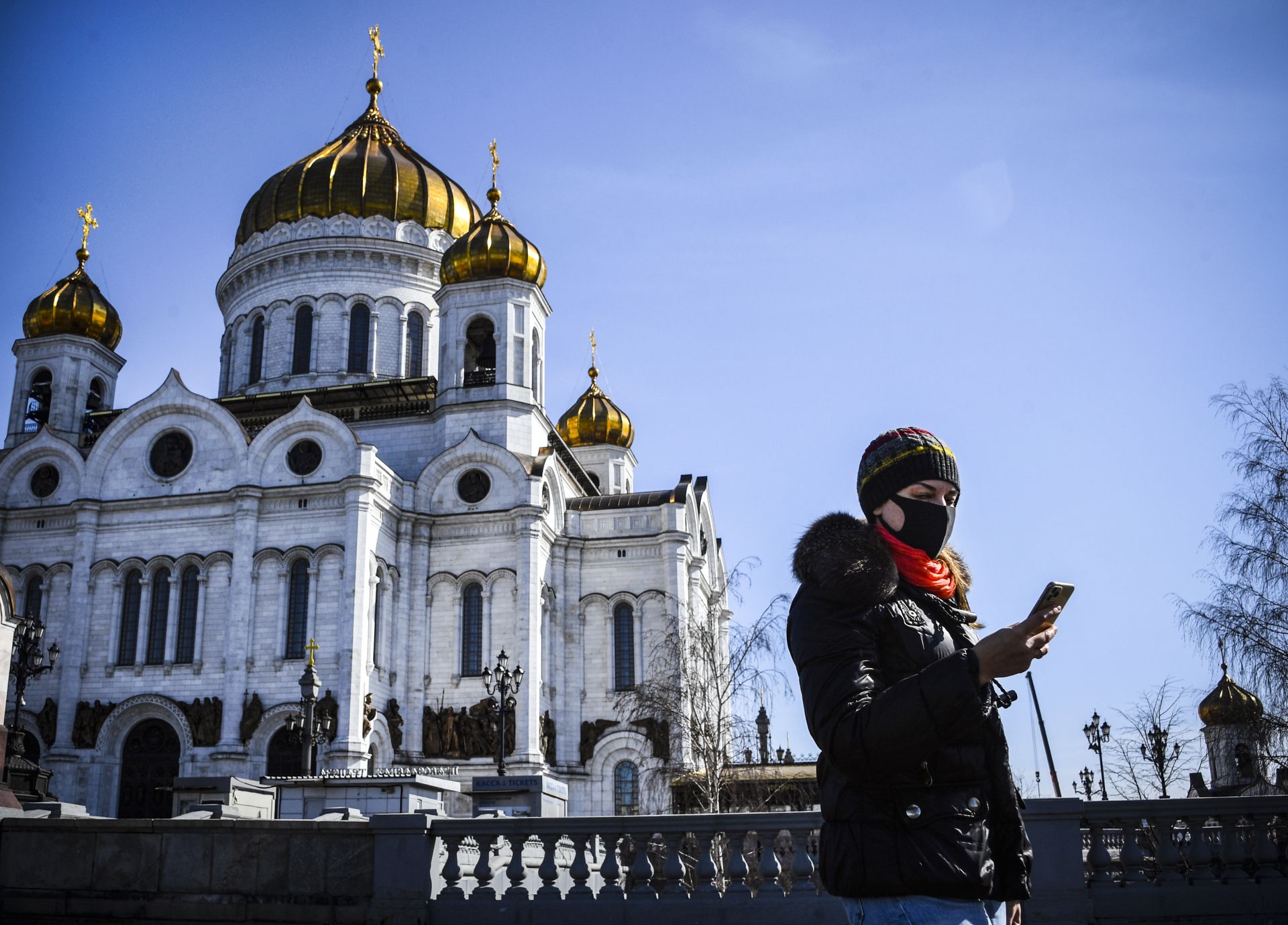 A woman wearing a face mask, amid concerns over the spread of the COVID-19 coronavirus, walks past the Cathedral of Christ the Saviour in downtown Moscow on March 26, 2020. (Photo by Alexander NEMENOV / AFP)