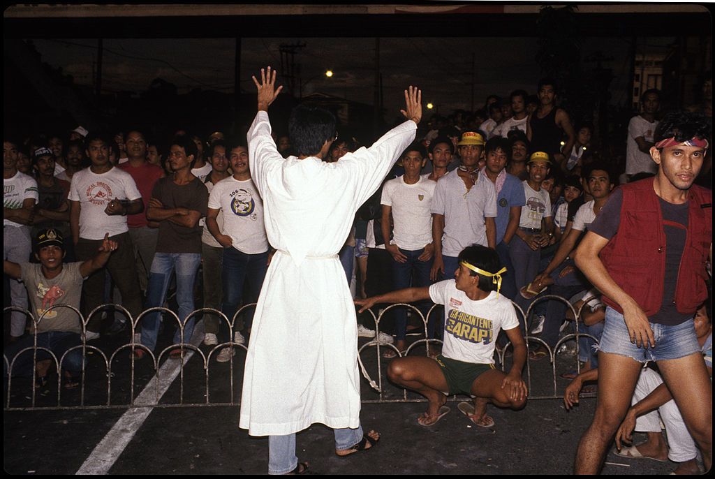 A Catholic priest calms a crowd of supporters of opposition leader Cory Aquino outside the Malacanang Palace. (Photo: Alex Bowie / Getty Images)