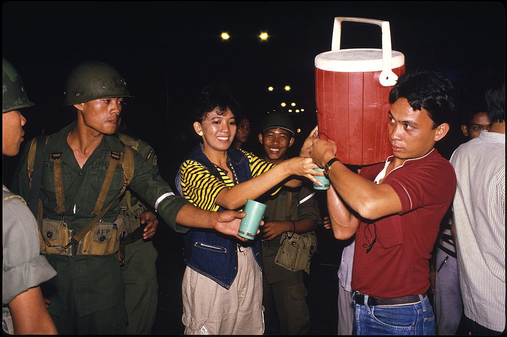 A Philippine soldier is provided with a drink by supporters of opposition leader Cory Aquino. (Photo: Alex Bowie / Getty Images)