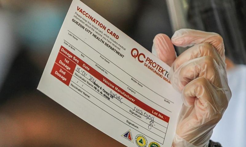A health worker shows a vaccination card before giving a dose of the Sinovac COVID-19 vaccine to resident in Manila, the Philippines on May 1, 2021. | Photo: Xinhua