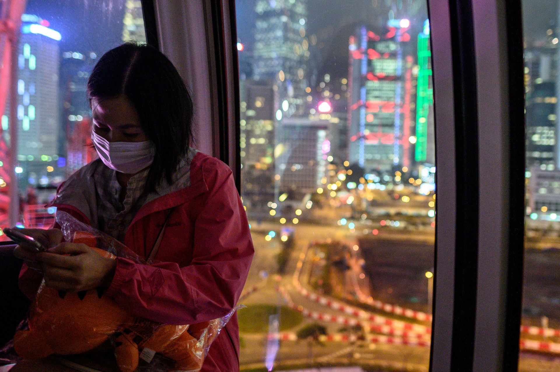 A woman wears a face mask as a preventative measure against the COVID-19 coronavirus, as she sits inside a cabin of the ferris wheel in Central district of Hong Kong on February 14, 2020. - The death toll from China's virus epidemic neared 1,400 on Friday with six medical workers among the victims, underscoring the country's struggle to contain a deepening health crisis. (Photo by Philip FONG / AFP)