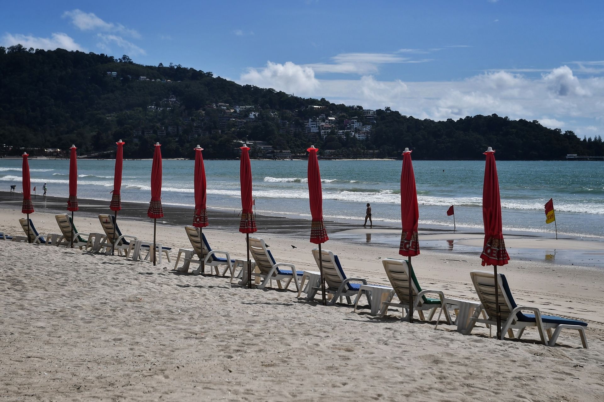 A lone tourist walks past deck chairs along an almost-empty Patong beach in Phuket on October 1, 2020, which has seen a lack of tourists due to ongoing restrictions relating to the COVID-19 novel coronavirus. (Photo by Lillian SUWANRUMPHA / AFP)