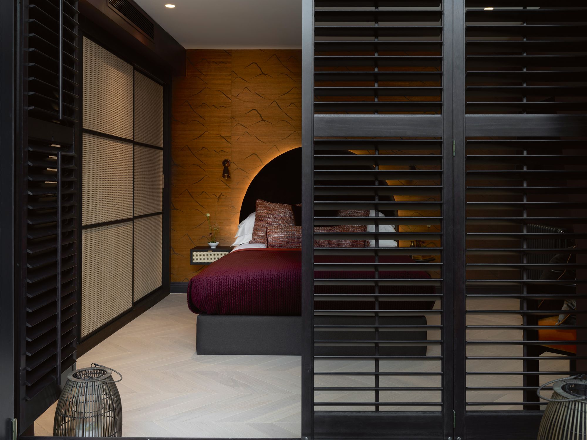 The guest bedroom features wallpaper from Elitis, a headboard upholstered in Lizzo velvet fabric and pillows in various fabrics by Jab and De Le Cuona