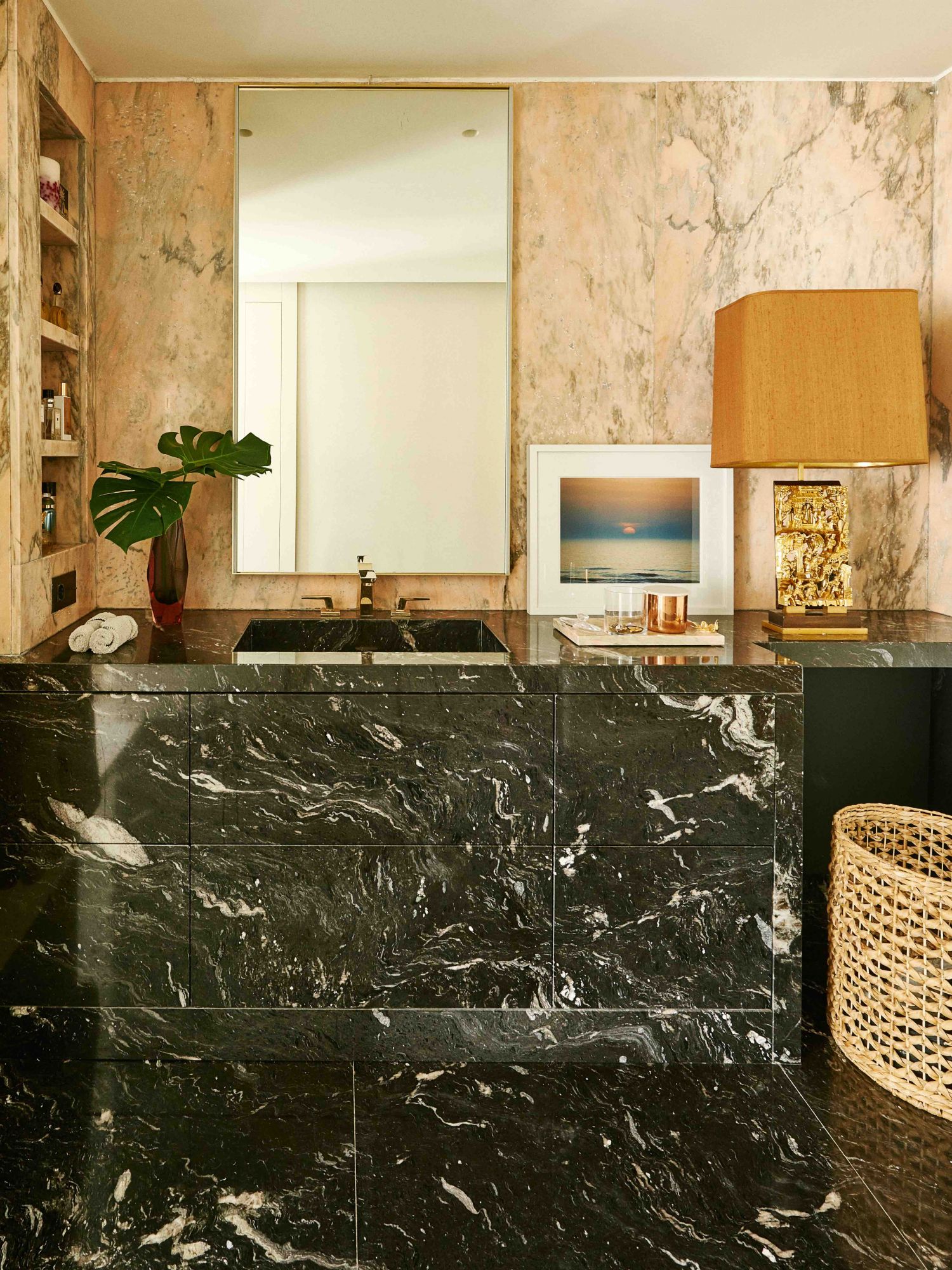 La salle de bain principale est un espace glamour avec du granit noir Cheyenne, des murs en marbre rose portugais et des robinets en or de Dornbracht