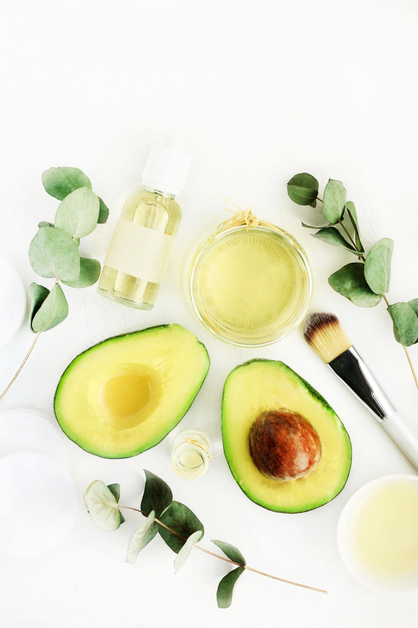 Cosmetic products on bottles with fresh avocado oil and eucalyptus aromatic leaves, white table ingredients top view. Natural skincare and beauty treatment; Shutterstock ID 1206641347; Purchase Order: -