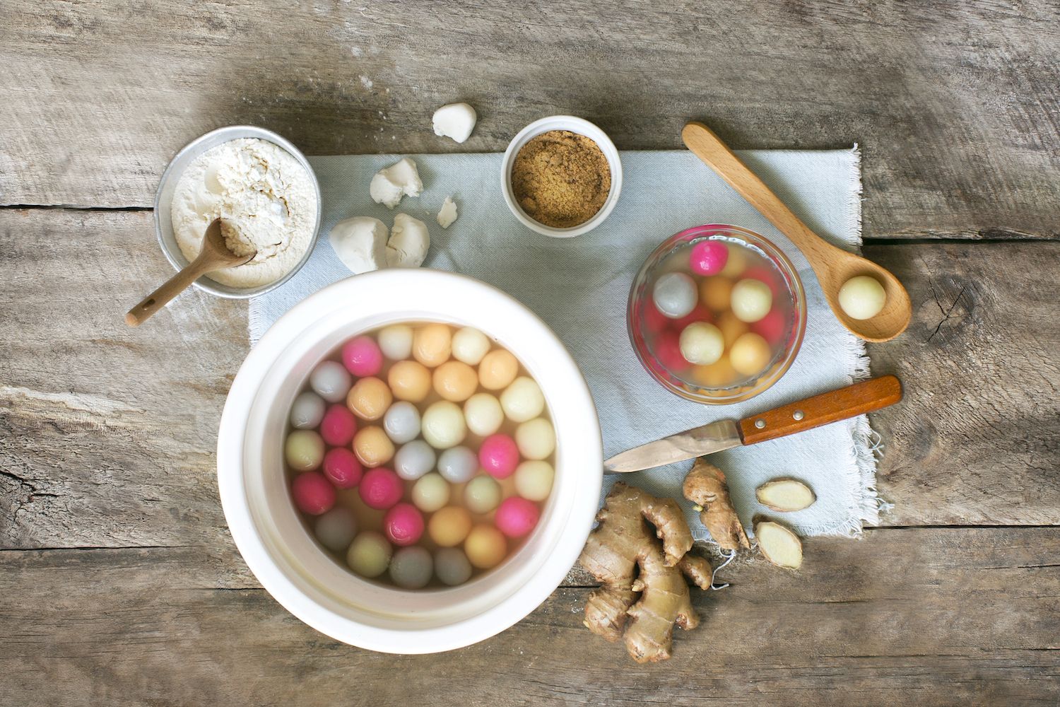 Flat lay Chinese new year food "tang yuan" colourful glutinous rice ball hot soup dessert on rustic wooden kitchen counter top.