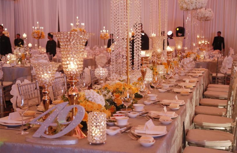 The grand ballroom was a glamorous yellow and silver mirage of candles, glittering chandeliers, fine china and bouquets upon bouquets of vibrant flowers.