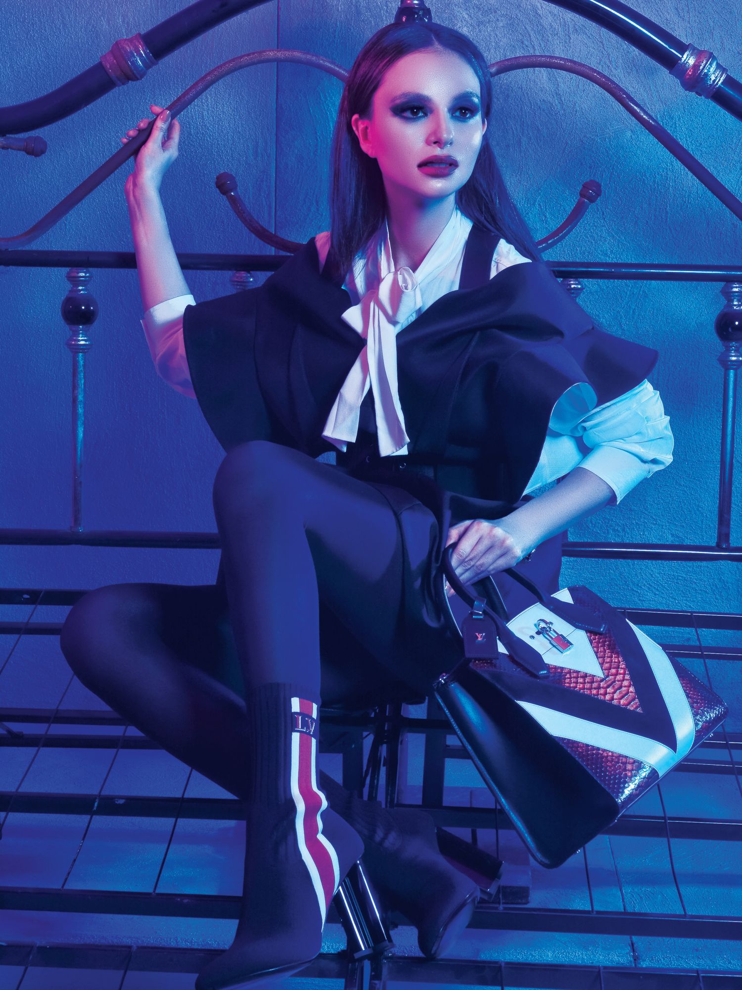 White pussy-bow blouse, black ruffled top with matching skirt, silhouette ankle sock boots, and python chevron City Steamer bag, all from Louis Vuitton