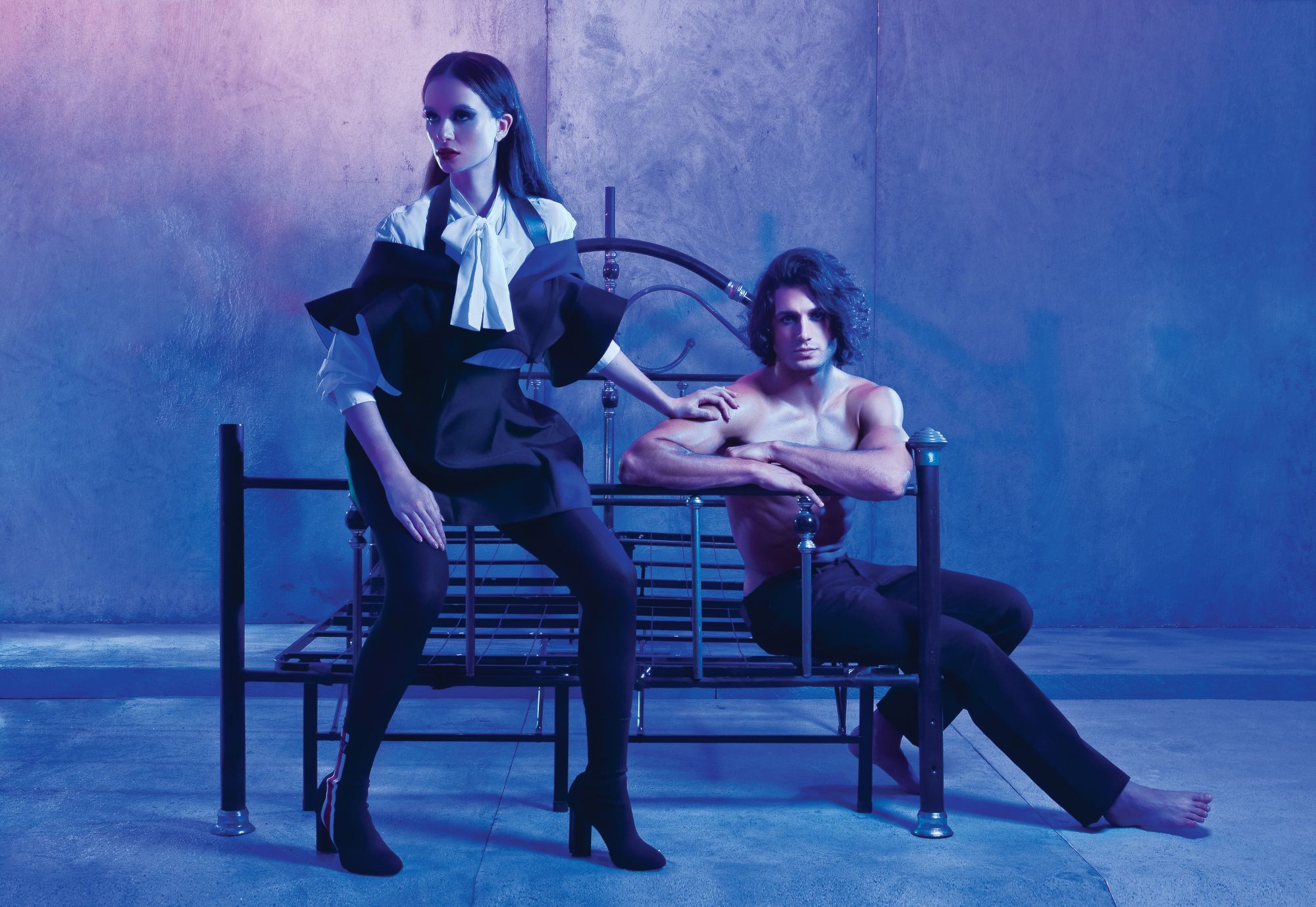 Valerie wears a white pussy-bow blouse, black ruffled top with matching skirt, silhouette ankle sock boots; Asaf wears black denim pants from Louis Vuitton