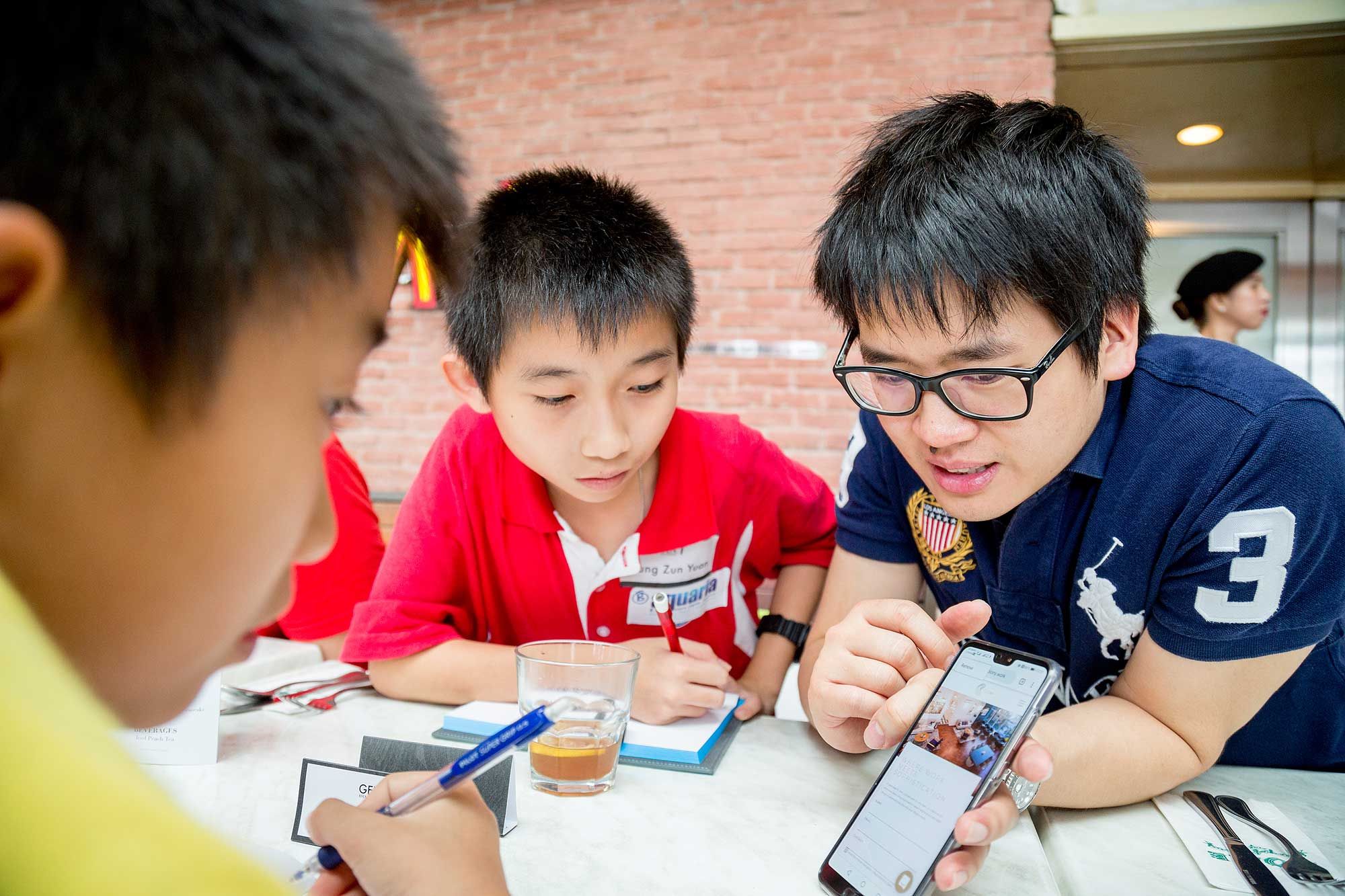 Timothy Tiah shows pictures of his work environment to his fascinated students.